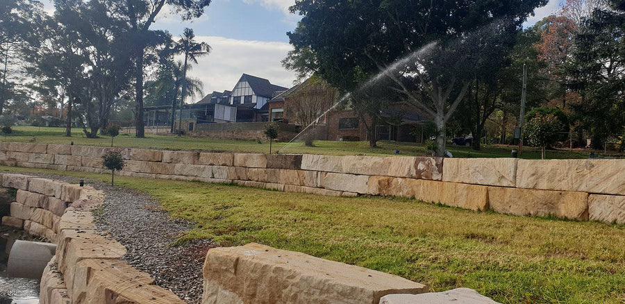 Sandstone block retaining wall beside a lawn in a residential garden